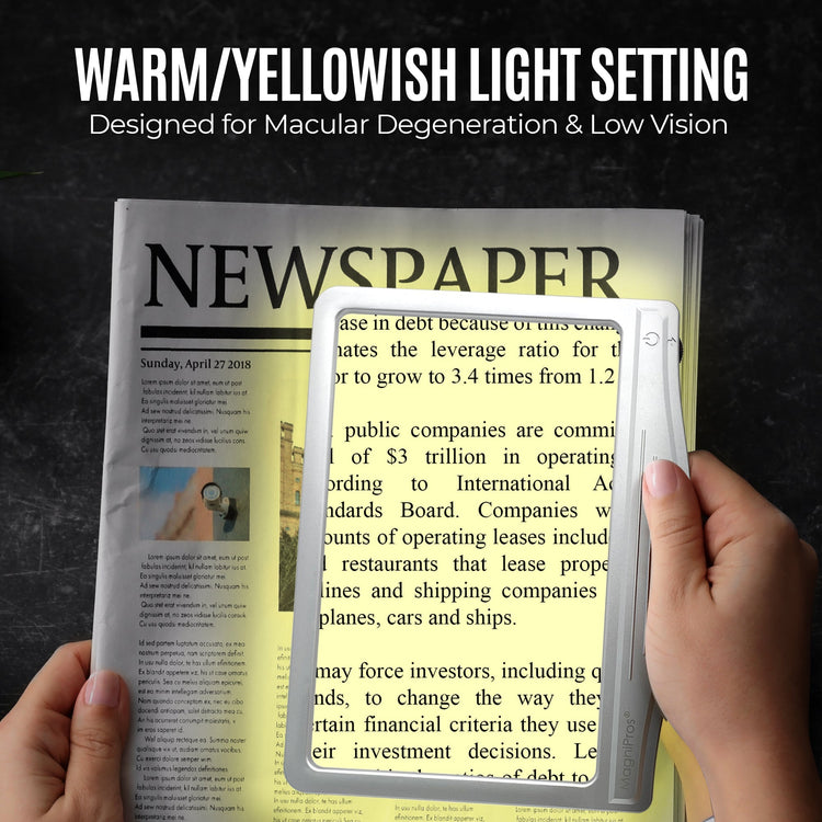 Hand holding a small light over a newspaper with text, set against a dark background.