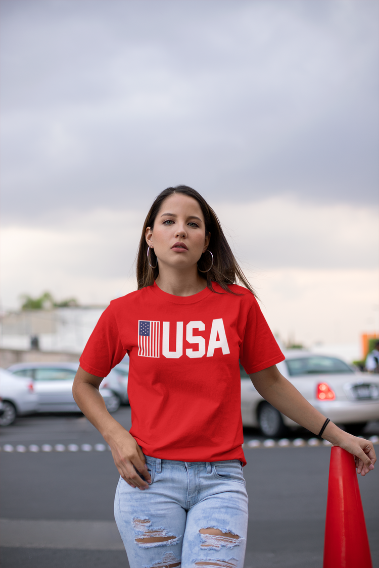 Person wearing a red 'USA' t-shirt with an American flag graphic outdoors.