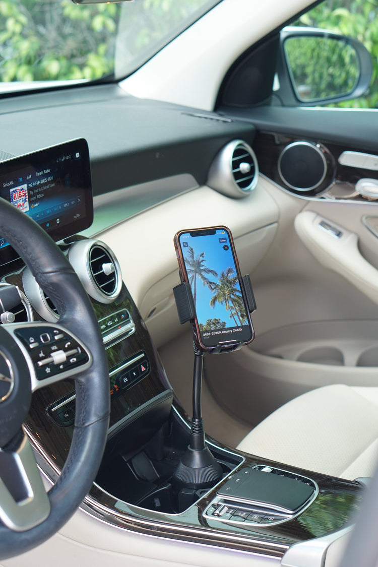 Car interior with a phone holder on the dashboard displaying a palm tree image.