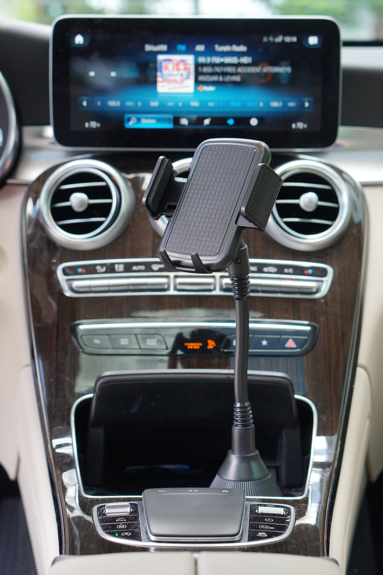 Car dashboard with a phone holder and navigation screen displaying a music app.