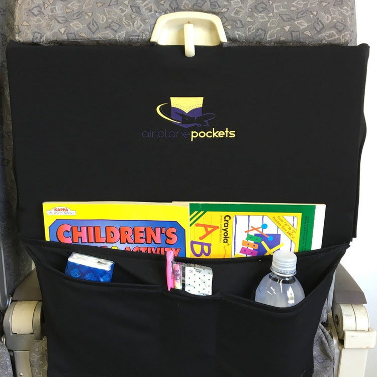 Black airplane pocket with children's books and a bottle, attached to an airplane seat.