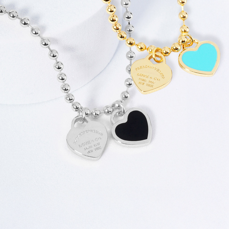 Two necklaces with heart-shaped charms on a white background
