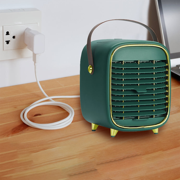 Green portable air conditioner on a wooden surface with a white wall and outlet in the background.