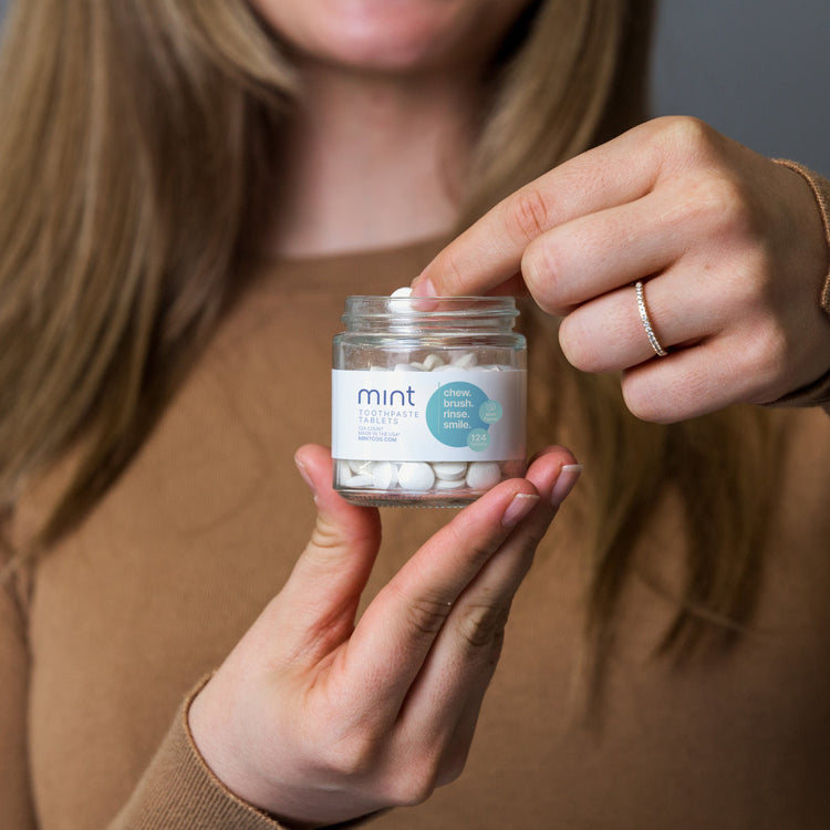 Person holding a jar of 'mint' products with a focus on the product label.