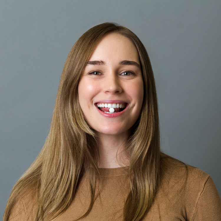 Woman with long brown hair wearing a brown sweater against a gray background