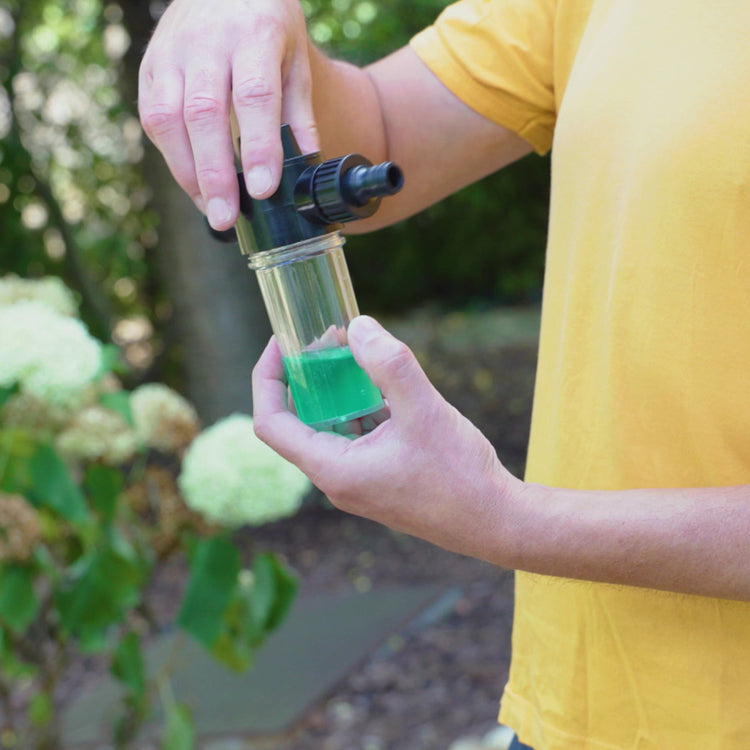 Person holding a green liquid in a transparent container outdoors