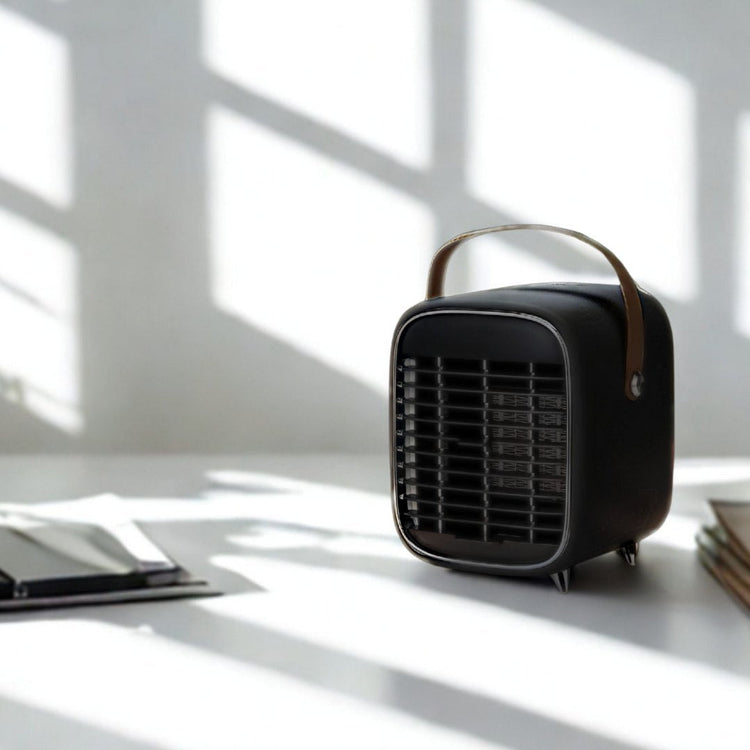 Black portable heater on a desk with a plant and tablet in a bright room