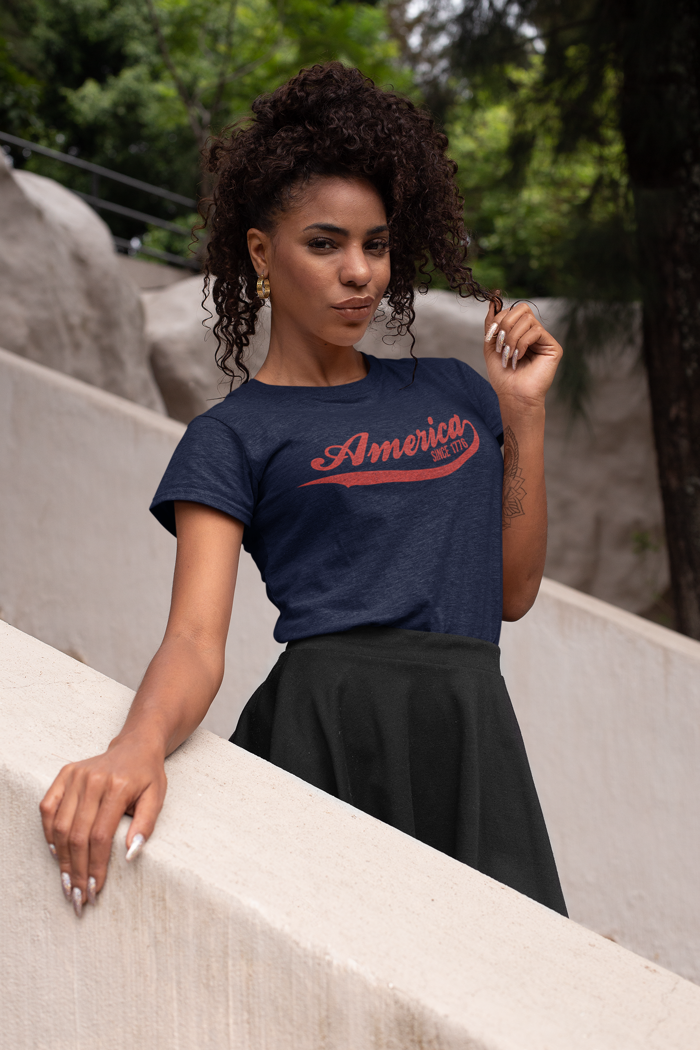 Woman wearing a navy blue t-shirt with 'America' printed in red, standing outdoors.
