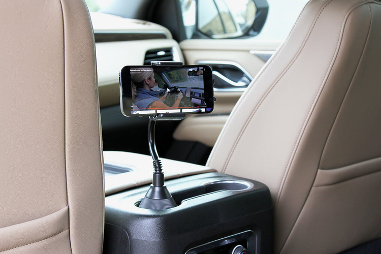 Phone mount on car dashboard displaying a video, with beige interior.
