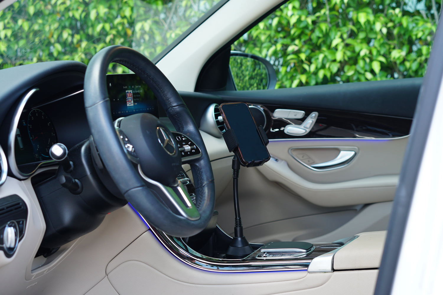 Car interior with steering wheel and dashboard, showing a phone mounted on the center console.