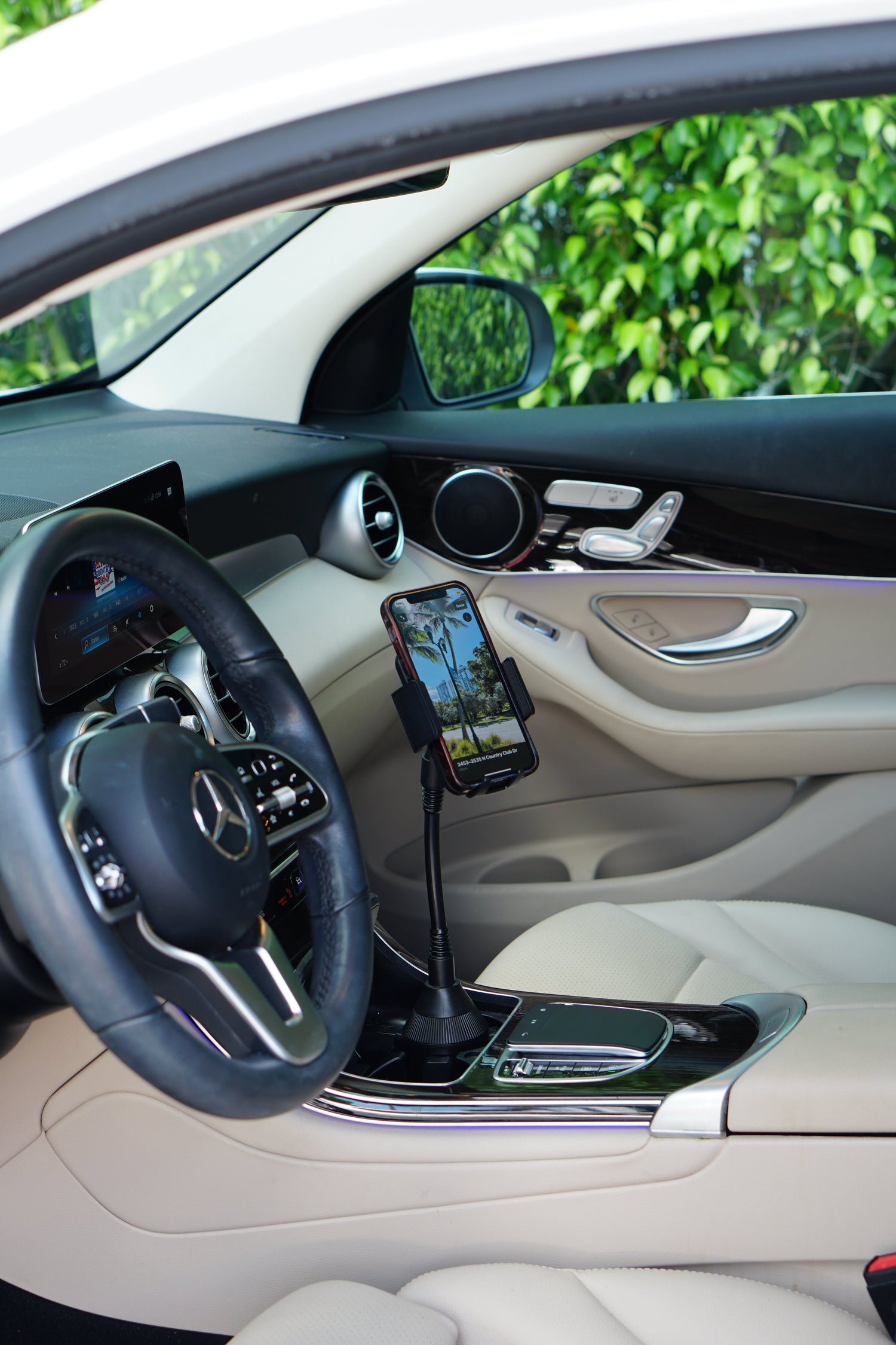 Car interior with a phone mounted on a holder, steering wheel, dashboard, and door panel.
