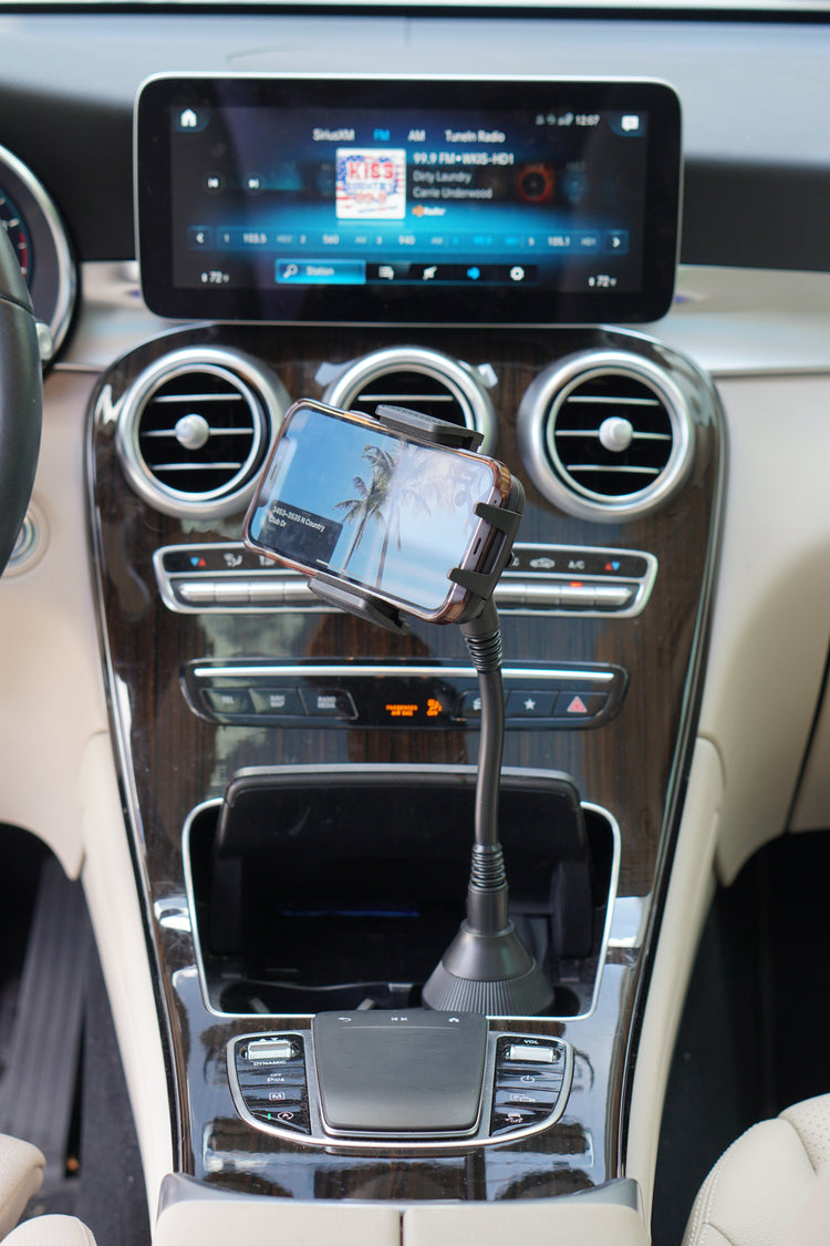 Car dashboard with a smartphone mounted on a car holder displaying a palm tree image.