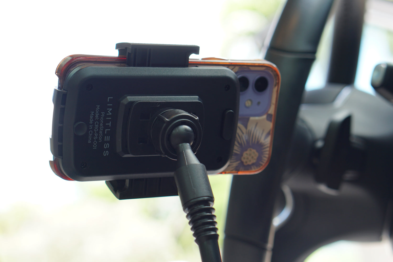 Phone mounted on a dashboard with a camera attached, inside a vehicle.