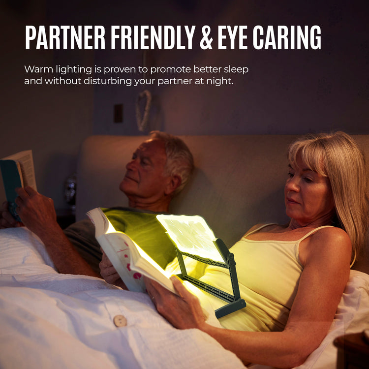 Two people in bed, one using a booklight to read, with text about partner-friendly and eye-careful lighting.