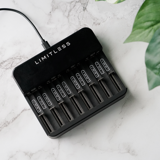 Black battery charger with multiple battery slots and Limitless branding, accompanied byLimitless batteries on a white background.