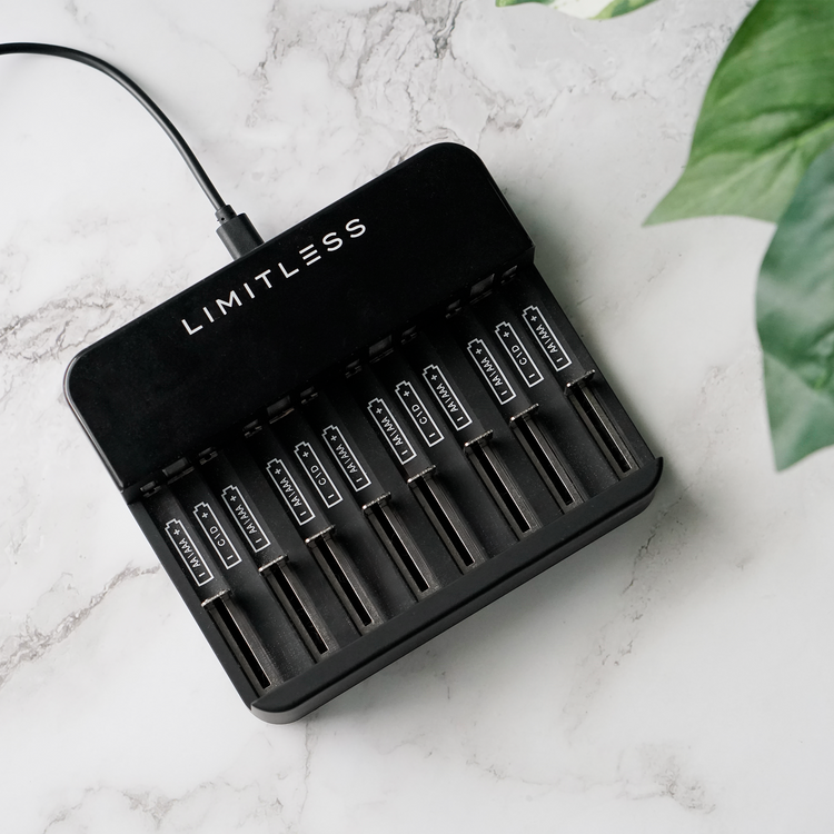 Black battery charger with 'Limitless' branding on a marble surface with green leaves.