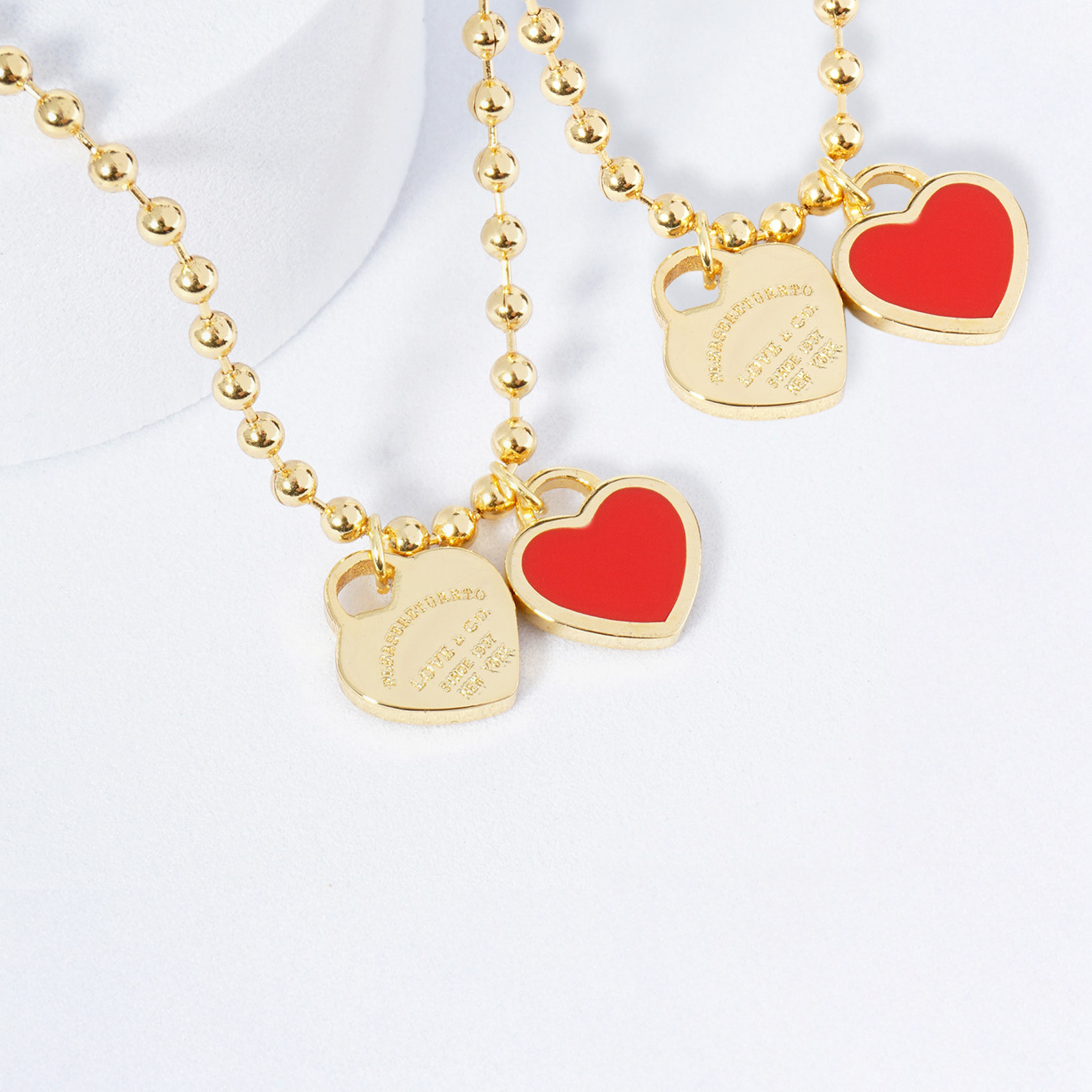 Gold necklace with red heart pendants on a white background