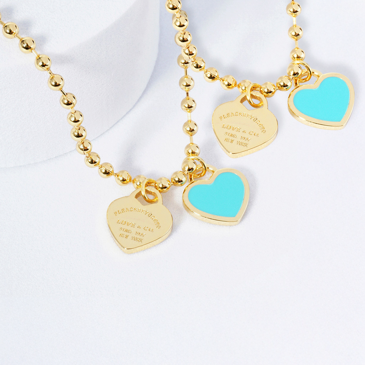 Gold necklace with turquoise heart charms on a white background