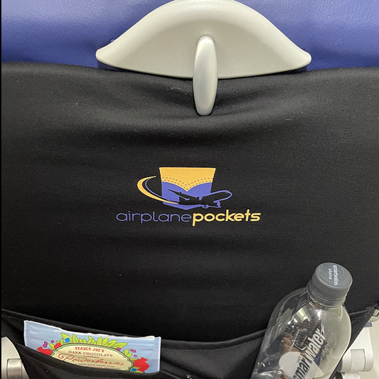 Airplane seat with 'airplane pockets' organizer holding a tablet, book, and drink.