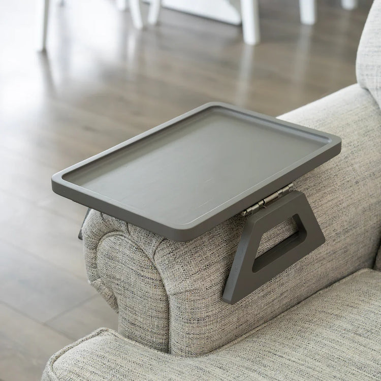 Gray tray attached to a couch armrest in a living room setting