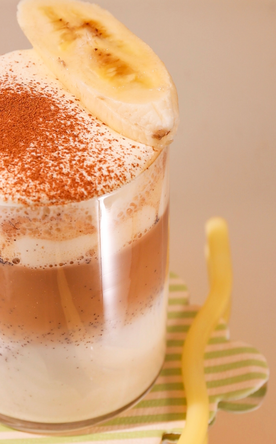 Close-up of a dessert with whipped cream and a banana slice on a beige background