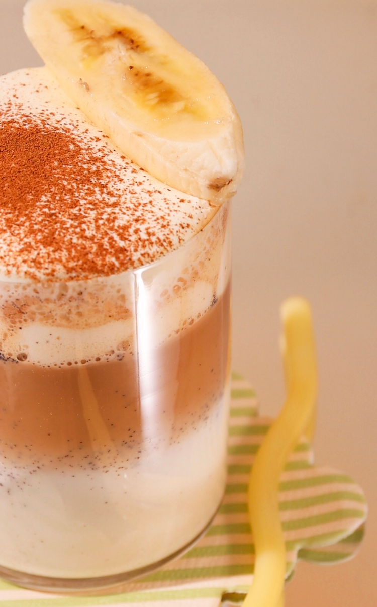 Close-up of a dessert with whipped cream and a banana slice on a beige background