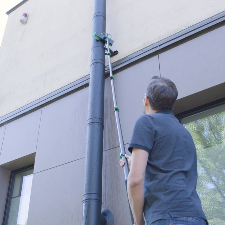 Person using a telescopic cleaning tool on a building exterior